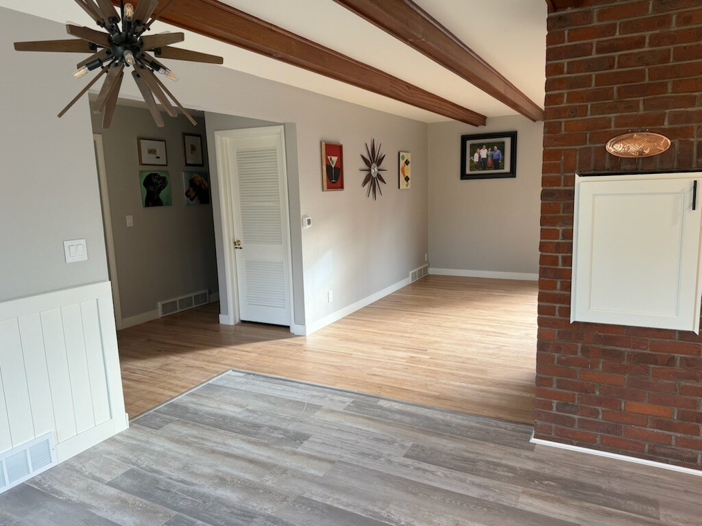 Living room flooring transition with exposed beam ceiling